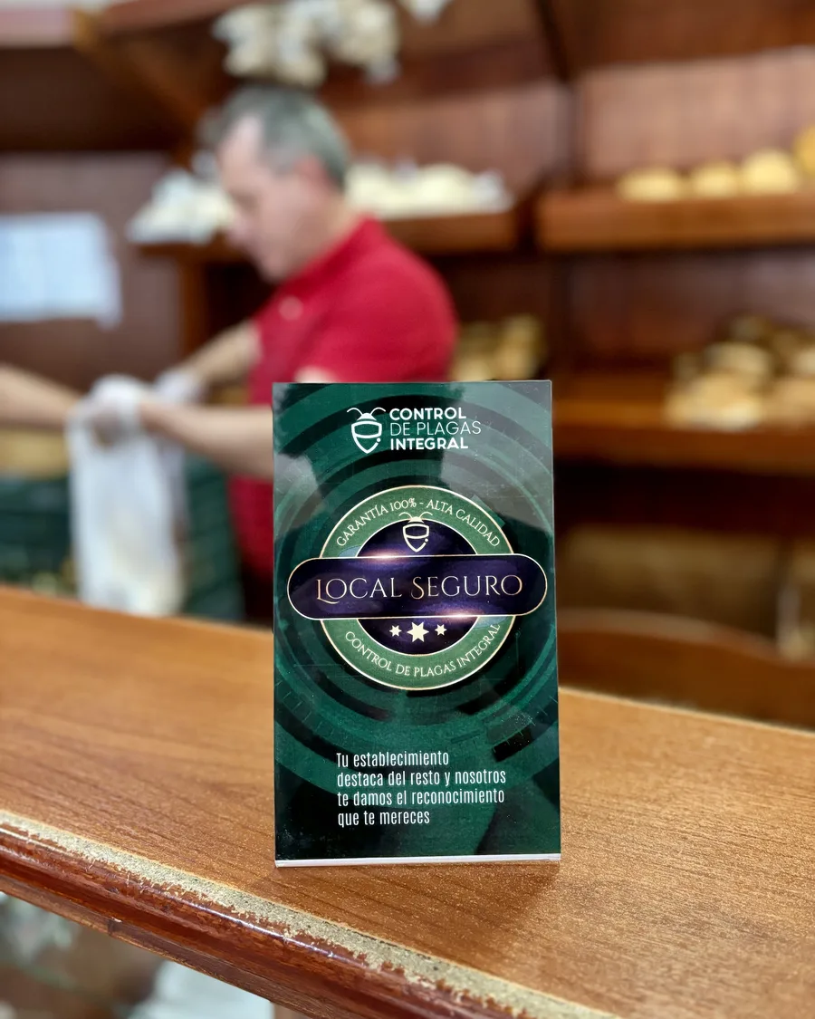 Insignia LOCAL SEGURO en una panadería mientras el personal atiende